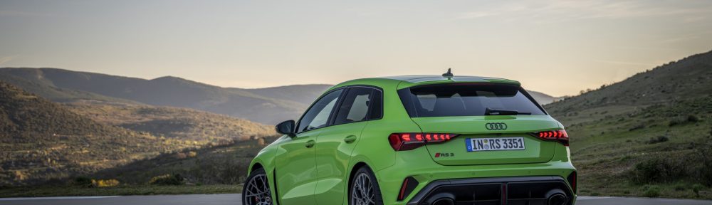 Vue 3/4 arrière de l'Audi RS3 Sportback 8Y MY24 de couleur verte sur la route en virage.