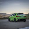 Vue 3/4 arrière de l'Audi RS3 Sportback 8Y MY24 de couleur verte sur la route en virage.