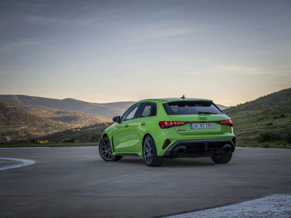 Vue 3/4 arrière de l'Audi RS3 Sportback 8Y MY24 de couleur verte sur la route en virage.