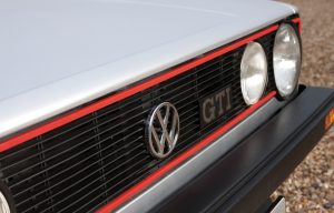 Logo Volkswagen "VW" sur la calanre noire cerclée de rouge de la Golf GTI 1 1800.